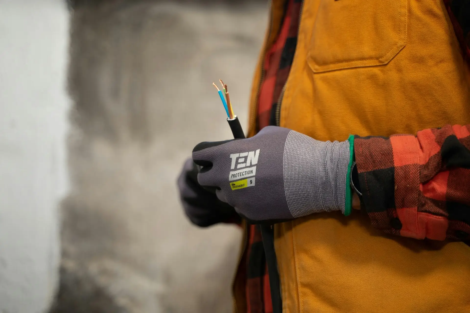 Elektryk w rękawiczkach, trzymający kabel elektryczny